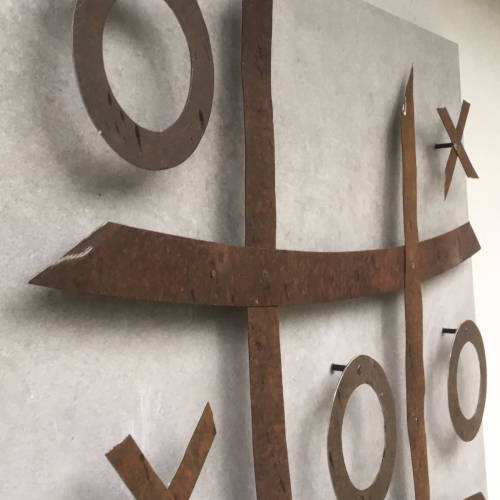 Wanddekoration: Tic-Tac-Toe-Spiel aus Cortenstahl auf heller Wand