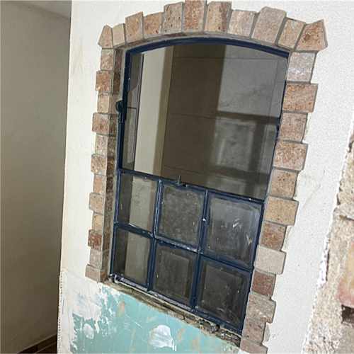 Altes Sprossenfenster mit Bogen, eingefasst in Ziegelsteine