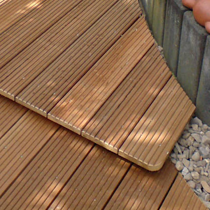 Terrasse aus geriffelten Holzdielen mit geschwungener Kante am Kiesbett