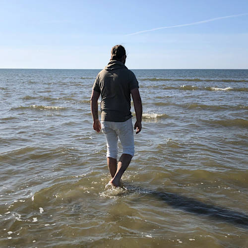 Lutz Kofalk watet barfuß ins Meer